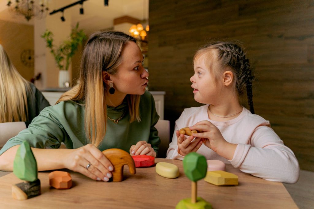 pexels-photo-6288088 An adult woman and a child with Down syndrome engaging in playful interaction with wooden toys indoors.
