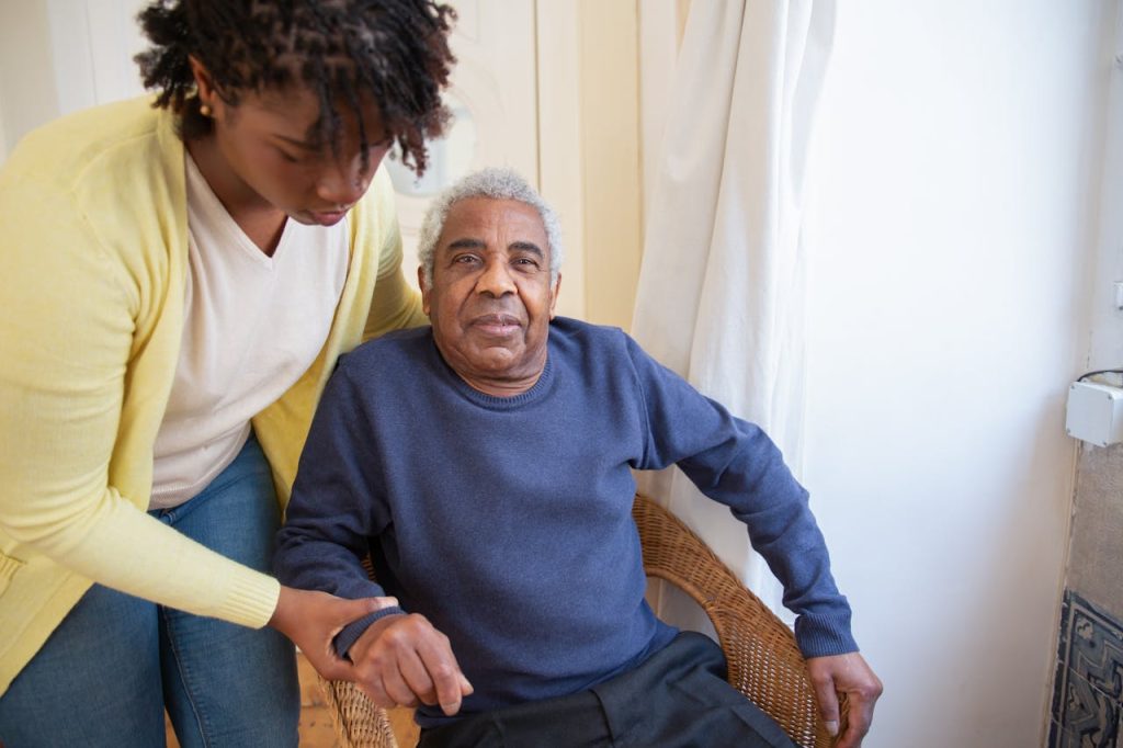pexels-photo-7551667 A woman assists an elderly man indoors, focusing on care and support.